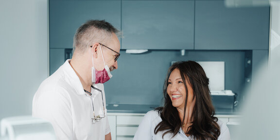 Zahnarzt im Beratungsgespräch mit Patientin im Behandlungszimmer