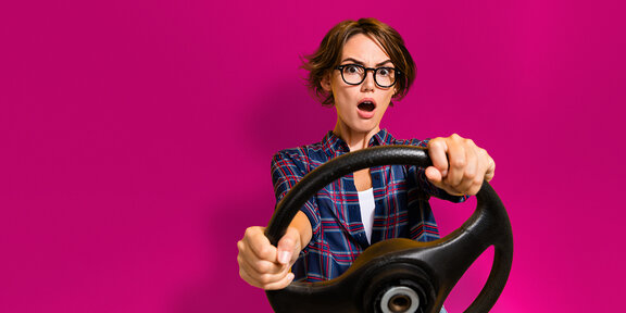 Praxisinhaberin am Lenkrad, symbolisiert Steuerung der eigenen Praxis